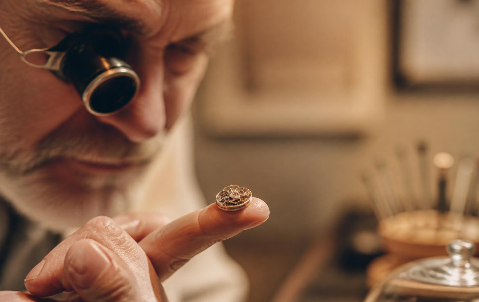 Zegarmistrz prezentujący mechanizm na opuszku palca